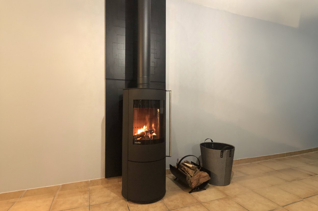 Poêle à bois moderne installé dans une pièce de vie avec conduit de fumée apparent dans le 64 (Pyrénées-Atlantiques).