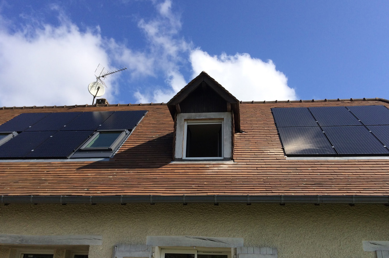 Panneaux photovoltaïques installés sur une toiture en pente autour d’une lucarne pour la production d’électricité solaire résidentielle dans le 64 (Pyrénées-Atlantiques).